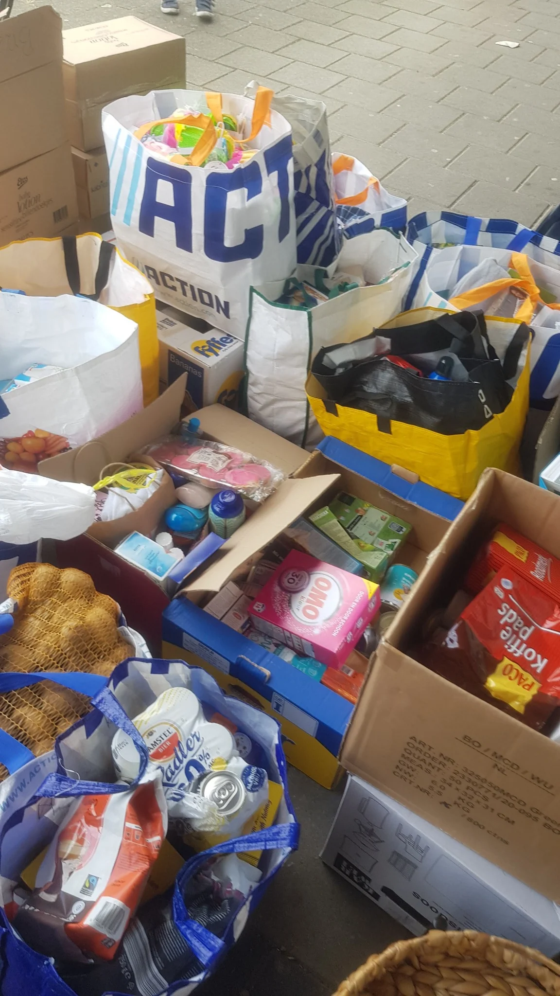 Dozen en tassen met levensmiddelen en huishoudelijke benodigdheden voor watersnoodhulp.